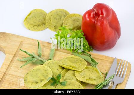 Italienische Pasta Ravioli mit grünem Kraut auf weißen Hintergrund/hausgemachte Pasta und Ravioli aus Holz mit Vintage Tasse Mehl und frischem Basilikum/Frisches p Stockfoto