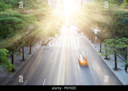 New York City Taxi beschleunigt die 42nd Street in Manhattan mit dem Sonnenuntergang im Hintergrund Stockfoto