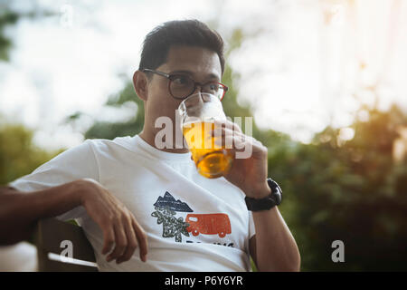 Junger Brillenbär man Bier trinkt. Stockfoto