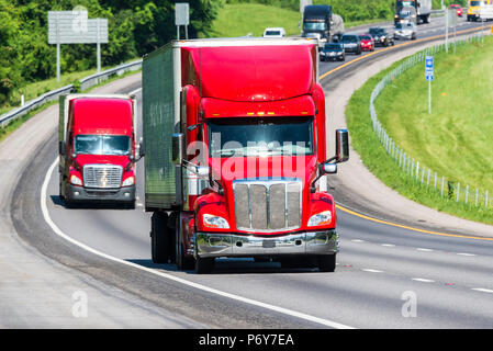 Zwei rote Lkw auf ein Tennessee interstate. Bild geschossen auf heißen Tag. Hitzewellen von Asphalt erstellen Verzerrungen, insbesondere bei Fahrzeugen, die weiter von der c Stockfoto