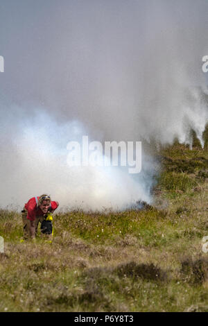 1. Juli 2018 - eine Bell UH-1 Iroquois Hubschrauber gießt 1000 Liter Wasser der Flammen im Winter Hill Feuer, verfehlte ein Feuerwehrmann, als Sie Enten auf den Boden. Feuer Besatzungen aus über Großbritannien haben im Winter Hill konvergierten die Flamme, die Meter pro Stunde wachsen zu steuern. Lancashire Feuer und Rettung und Lancashire Polizei führen die Antwort auf die 'Major Incident'. Stockfoto