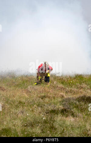 1. Juli 2018 - eine Bell UH-1 Iroquois Hubschrauber gießt 1000 Liter Wasser der Flammen im Winter Hill Feuer, verfehlte ein Feuerwehrmann, als Sie Enten auf den Boden. Feuer Besatzungen aus über Großbritannien haben im Winter Hill konvergierten die Flamme, die Meter pro Stunde wachsen zu steuern. Lancashire Feuer und Rettung und Lancashire Polizei führen die Antwort auf die 'Major Incident'. Stockfoto