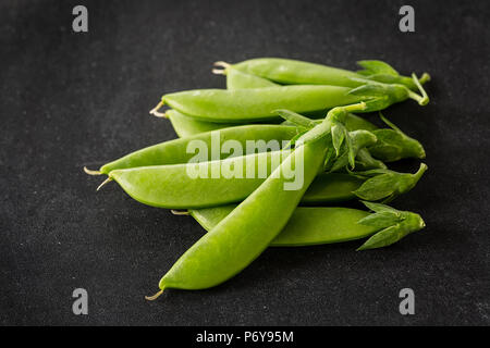 Frisch Schnee Erbsen auf einem schwarzen Hintergrund ausgewählt. Stockfoto