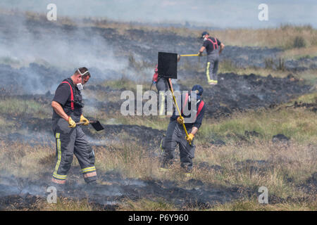 1. Juli 2018 - Feuerwehrmänner Schlacht Flammen auf der Winter Hill Feuer. Feuer Besatzungen aus über Großbritannien haben im Winter Hill konvergierten die Flamme, die Meter pro Stunde wachsen zu steuern. Lancashire Feuer und Rettung und Lancashire Polizei führen die Antwort auf die 'Major Incident'. Stockfoto