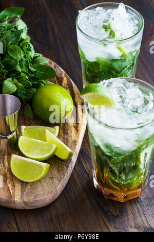 Dirty Mojito und Zutaten (frische Minze, geschnitten Kalk) auf einem dunklen Holzbrett serviert. Hohe Auflösung. Stockfoto