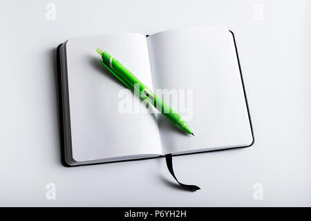 Leere Notiz Buch mit grünem Stift auf weißem Hintergrund shot oben öffnen Stockfoto