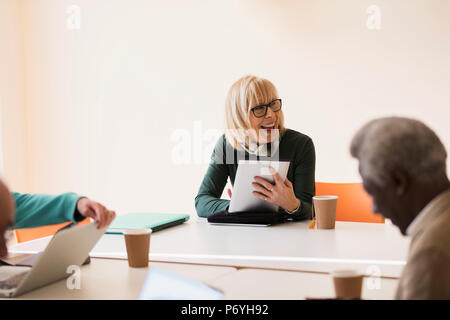 Lächelnd, zuversichtlich senior Geschäftsfrau mit digitalen Tablet führende Konferenz zimmer konferenz Stockfoto