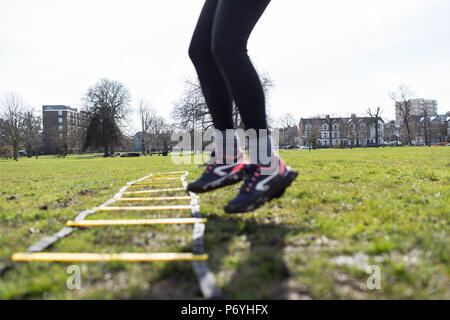Frau mit der Ausübung Leiter in Park Stockfoto