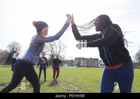 Begeisterte Frauen, high-Fiving, trainieren im sonnigen Park Stockfoto