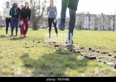 Mannschaft zujubeln Frau tun Geschwindigkeit Leiter Bohren im sonnigen Park Stockfoto