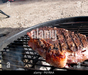New York Steak Kochen im Freien auf Holzkohle Grill Stockfoto