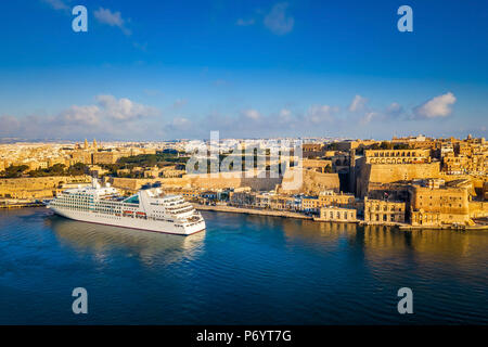 Valletta, Malta - Kreuzfahrtschiff in den Grand Harbour bei Sonnenaufgang mit der antiken Stadt Valletta im Hintergrund Stockfoto