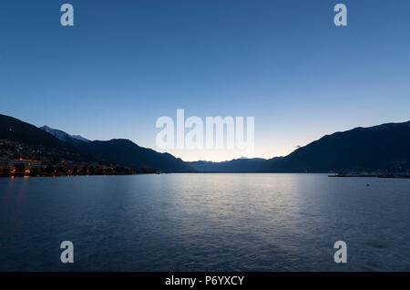 Alpine Lago Maggiore mit Blick auf die Berge in der Abenddämmerung in Ascona, Schweiz. Stockfoto