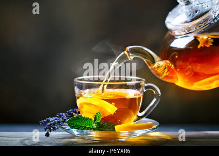 Prozess der Zubereitung von Tee, Tee Zeremonie. Tasse frisch gebrühter schwarzer Tee, warmes, weiches Licht. Stockfoto