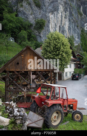 Eine der kommunistischen Ära Traktor ist neben einem traditionellen slowenischen Dorf Scheune geparkt, am 18. Juni 2018, in Bohinjska Bela, Bled, Slowenien. Stockfoto