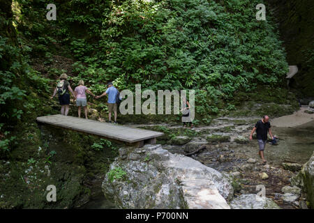 Abenteuerliche Wanderer verhandeln moderates Terrain in der felsigen Schlucht in der Nähe des 15 m hohen Wasserfall Kozjak, Teil der Kobarid Heritage Trail, am 21. Juni 2018, in Kobarid, Slowenien. Stockfoto