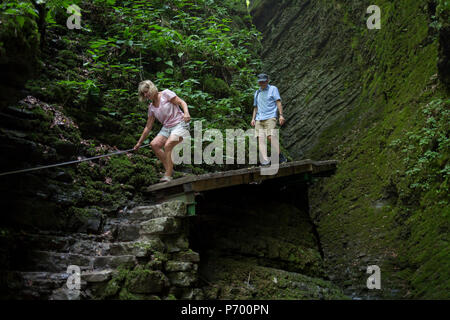Abenteuerliche Wanderer verhandeln moderates Terrain in der felsigen Schlucht in der Nähe des 15 m hohen Wasserfall Kozjak, Teil der Kobarid Heritage Trail, am 21. Juni 2018, in Kobarid, Slowenien. Stockfoto