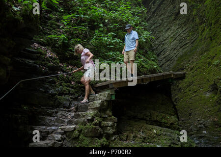 Abenteuerliche Wanderer verhandeln moderates Terrain in der felsigen Schlucht in der Nähe des 15 m hohen Wasserfall Kozjak, Teil der Kobarid Heritage Trail, am 21. Juni 2018, in Kobarid, Slowenien. Stockfoto