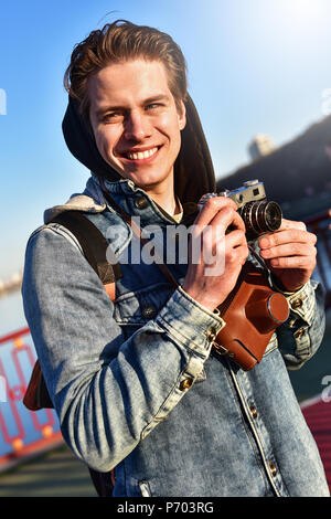 Stilvolle mann Fotografieren auf retro Kamera. Touristischen Aufenthalt auf der Brücke und ein Foto machen. Stockfoto