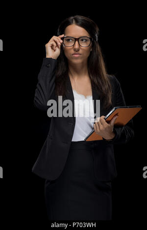 Attraktive zuversichtlich Geschäftsfrau in Brillen Holding digital Tablet, isoliert auf Schwarz Stockfoto