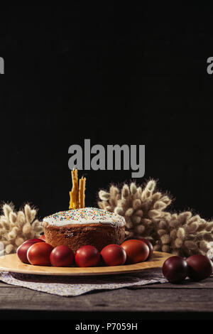 Bemalte Hühnereier, Ostern Kuchen und Kerzen auf hölzernen Tisch Stockfoto