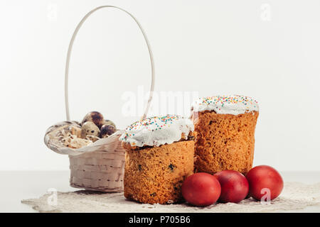 Wachtel Eier im Korb, Ostern Kuchen und bemalte Hühnereier auf Grau Stockfoto