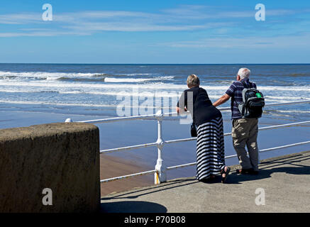 Paar auf Pier, blickt auf das Meer, Whitby, North Yorkshire, England, Großbritannien Stockfoto