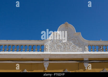 Weiße Farbe der reich verzierten Detail von einem Zaun eines portugiesischen Haus mit einem gelben Fassade. Strahlend blauen Himmel. Castro Marim, Algarve, Portugal. Stockfoto