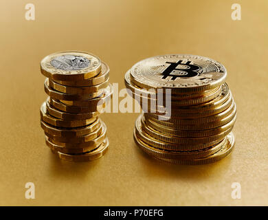 Golden Bitcoins neben British Pound Münzen gestapelt Stockfoto