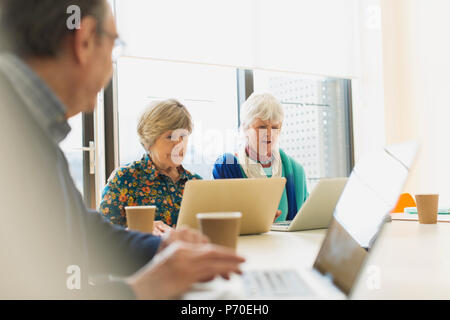 Senior Unternehmerinnen mit Laptops im Konferenzraum treffen Stockfoto