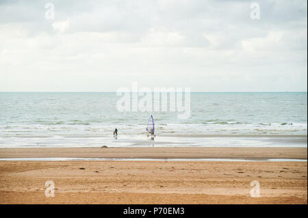 Surfen am Strand vor der Wellen im Herbst mit einigen Menschen zu Fuß durch Stockfoto