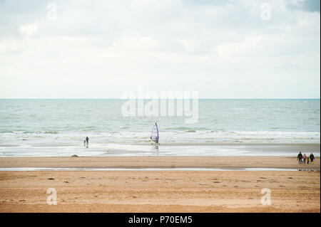 Surfen am Strand vor der Wellen im Herbst mit einigen Menschen zu Fuß durch Stockfoto