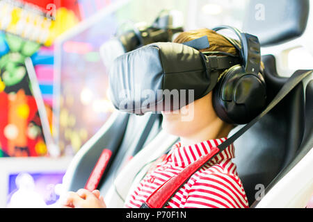 Erstaunt jugendlich Junge schreien, das Tragen von Virtual Reality goggles Filme, Standortwahl in 4D Stuhl. Stockfoto