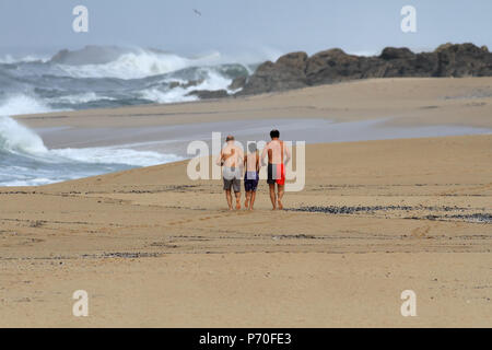 Matosinhos, Portugal - Oktober 19, 2014: Drei männliche Personen, zwei Erwachsene und ein junger Mann, der auf einem einsamen Strand im Norden Portugals Stockfoto