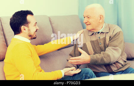 Im Alter von Vater und seinem jungen Sohn gemütlich zu Hause auf der Couch kommunizieren Stockfoto