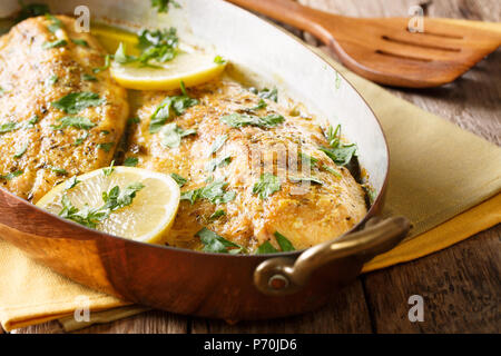 Lecker Fisch: gebackene Forelle Filets mit Knoblauch buttrige Kräutersoße, Zitrone und Petersilie close-up in einem Kupfer Pfanne. Horizontale Stockfoto