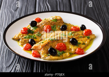 Leckeres Essen: Forelle Fisch mit Knoblauch Zitrone butter Soße, Tomaten, Petersilie und Oliven closeup auf einem Teller auf dem Tisch. Horizontale Stockfoto