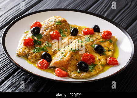 Italienische forellenfilet Fisch mit Knoblauch Zitronensauce, Tomaten, Petersilie und Oliven close-up auf einem Teller auf dem Tisch. Horizontale Stockfoto