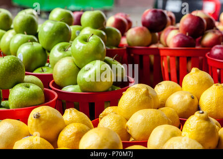 Zitronen in einem Korb mit grünen und roten Äpfel im Hintergrund. Stockfoto