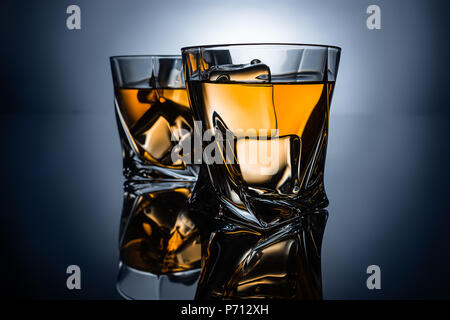 Zwei Gläser Whisky mit Eiswürfel, auf dunkelgrauem Hintergrund Stockfoto