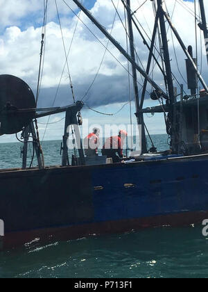 Zwei Besatzungsmitglieder von Coast Guard Cutter Eiche ein Feuer an Bord des Fischereifahrzeugs Juniper Schlacht nach dem Maschinenraum Feuer in Nantucket Sound am 11. Mai 2017 gefasst. Der Kapitän meldete das Feuer über Ch.16 Um 8:50 Uhr, keine Verletzungen gemeldet wurden. Stockfoto