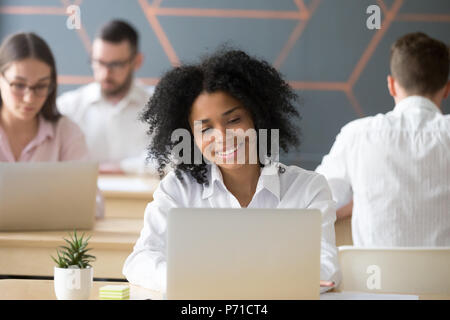 Gerne Afrikanische amerikanische Arbeiter das Chatten mit Freunden am Laptop Stockfoto