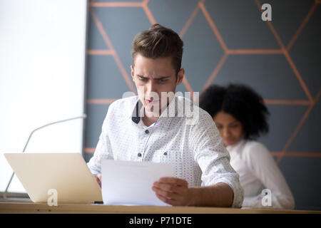 Männliche Mitarbeiter lesen Statistiken Dokument in Office Stockfoto