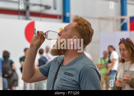 Kiew, Ukraine - Juni 02, 2018: Die junge rothaarige Mann schmeckt Weißwein in Kiew Weinfest. 77 Winzer aus der ganzen Welt nahmen an der großen f Stockfoto