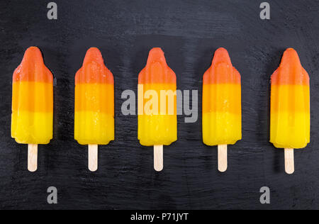 Obst Eis auf Stick auf schwarzem Schiefer. Fokus auf Eis am Stiel. Stockfoto