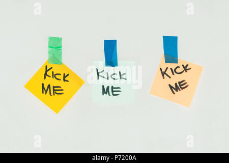 Nahaufnahme, Ansicht von Noten mit kick mich Schriftzug und Klebeband auf grau, April Fools Day holiday Konzept isoliert Stockfoto
