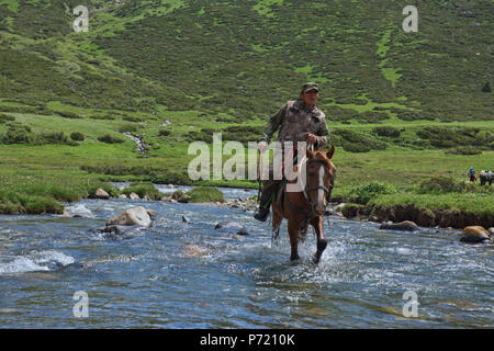 Kirgisische horserider Überquerung der Tup Fluss, Jyrgalan Tal, Kirgisistan Stockfoto