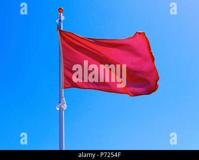 Red unsichere Flagge gegen den blauen Himmel fliegen zu baden Stockfoto