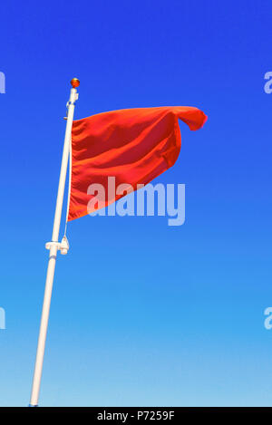 Red unsichere Flagge gegen den blauen Himmel fliegen zu baden Stockfoto