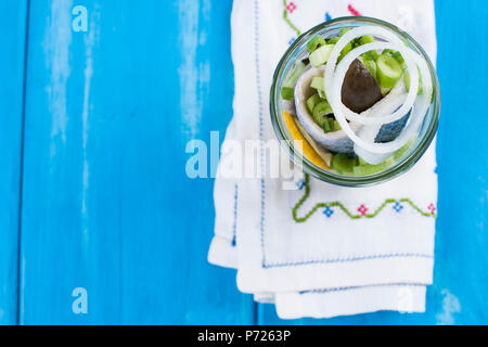 Traditionelle niederländische marinierten Hering mit Zitrone und Zwiebeln in einem jar. Fisch auf blauem Hintergrund. Platz kopieren Stockfoto